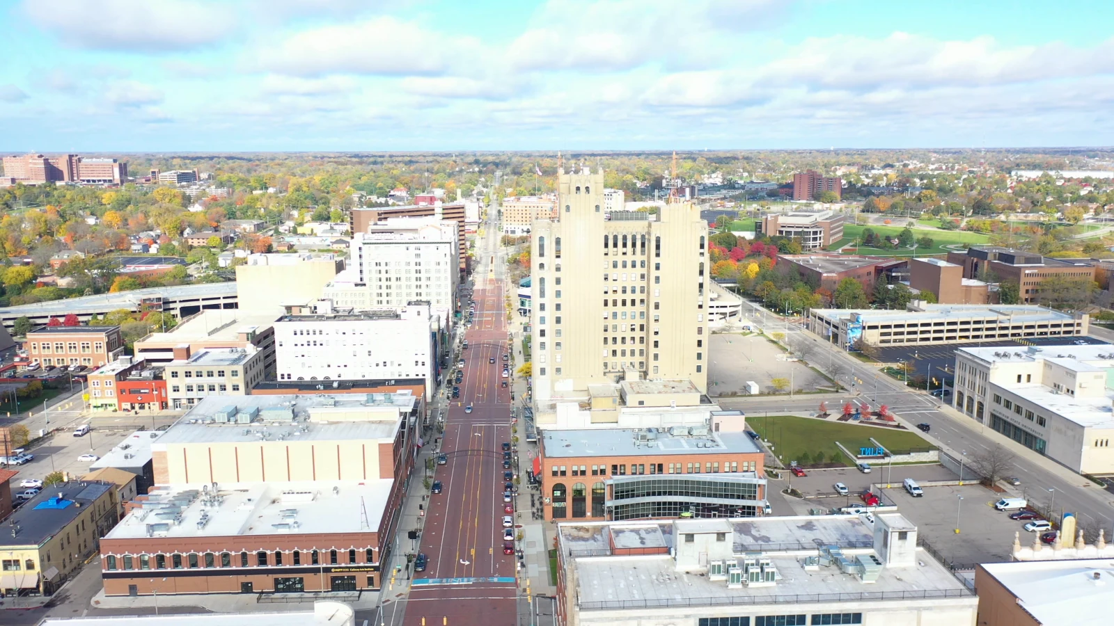 Aerial view over downtown Flint, with the city skyline and autumn trees beyond